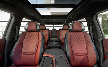 View of the dark black and red cabin seats, middle console, and sunroof in the 2025 INFINITI QX80.